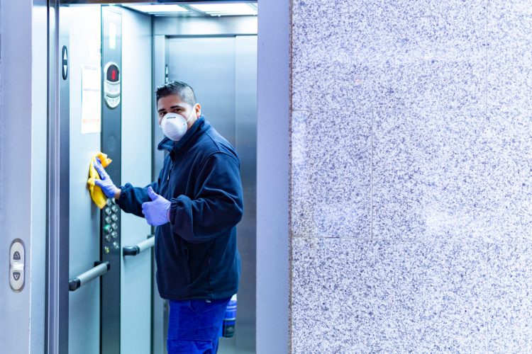worker disinfecting elevator to avoid contagion of coronavirus