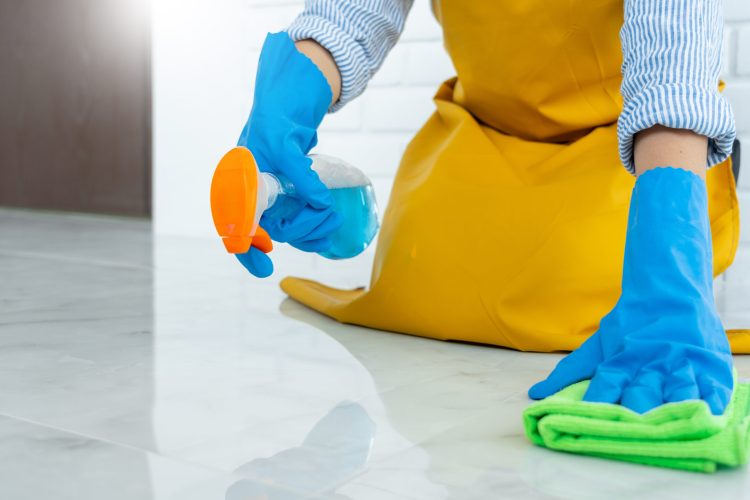 Housekeeper maid wearing rubber gloves with cloth cleaning or applying floor care and cleaners at home, housework and housekeeping concept